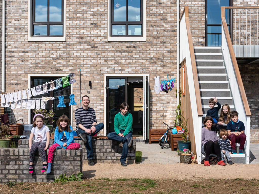 Happy families sat besides their homes at Marmalade Lane