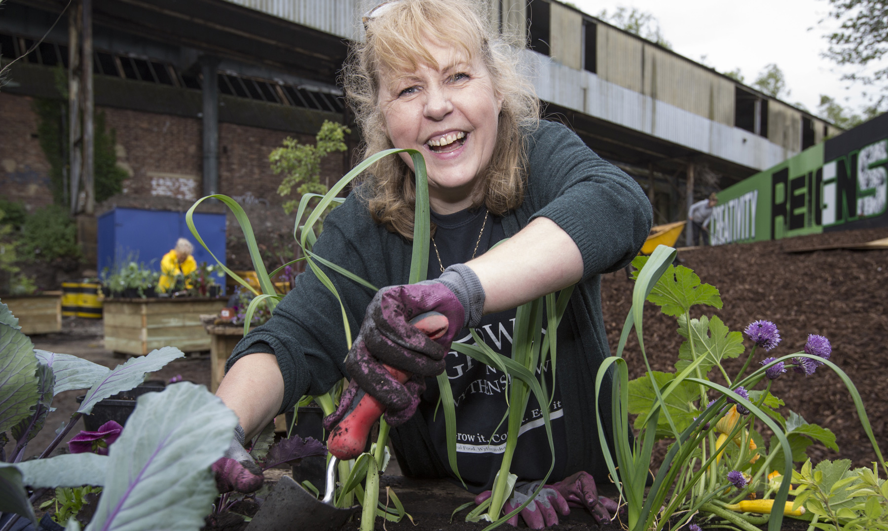 Happy lady planting flowers in an urban allotment